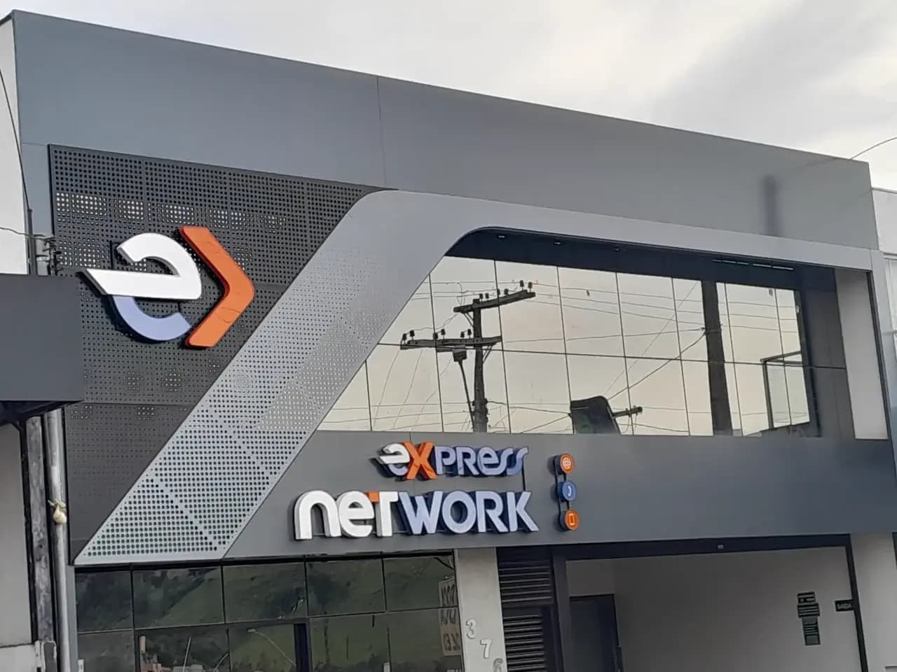 Totem comercial metálico e iluminado na entrada de uma empresa à noite, transmitindo credibilidade